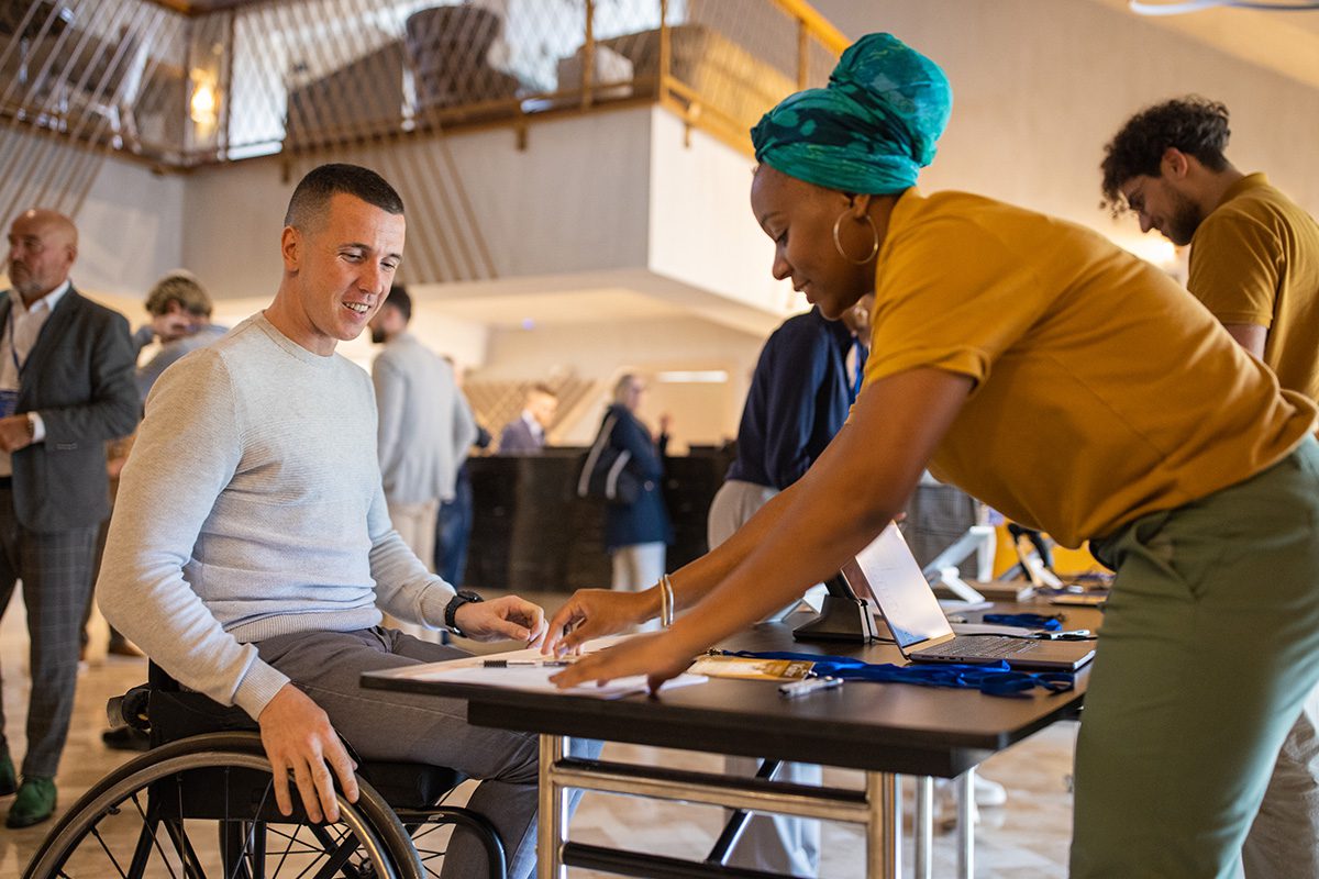 Person in wheelchair registering at event table.