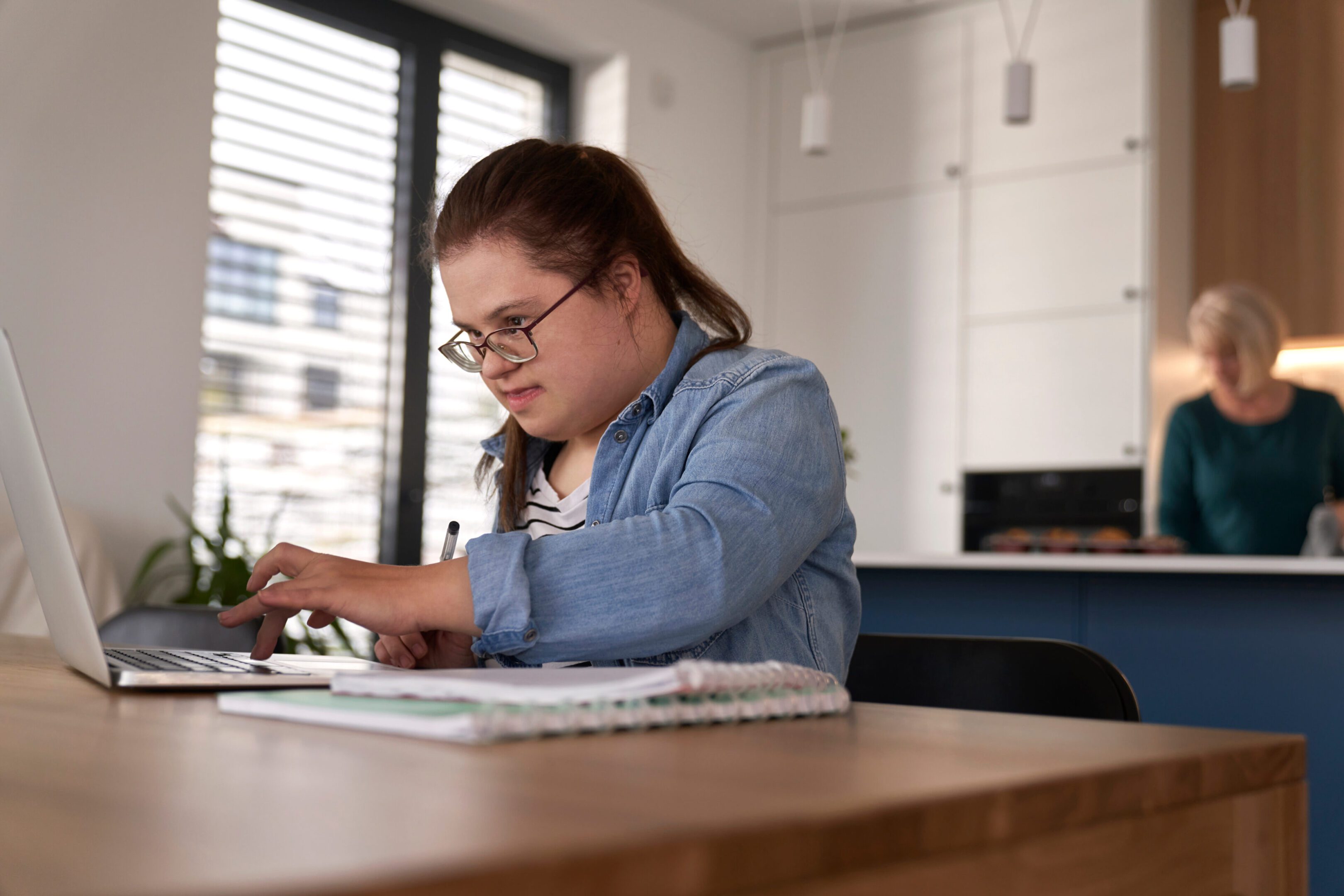 A focused woman working on a project at a desk indoors.